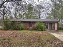 Single story brick home with covered front entrance and attached garage sits on a large wooded lot at 307 Brook St, Salisbury, NC 28146