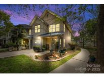Charming two-story townhome featuring well-lit exterior, landscaped yard, and inviting front porch at twilight at 3414 Chagall Ct, Charlotte, NC 28205