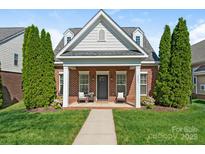 Charming brick home featuring a cozy front porch with seating and meticulously maintained landscaping at 4303 Patriots Hill Rd, Mint Hill, NC 28227