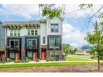Modern townhome with a brick facade, black framed windows, and a vibrant orange front door at 648 W End Dr, Charlotte, NC 28208