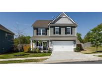 Charming two-story home with a covered front porch, attached two-car garage, and manicured landscaping at 325 Crandon Rd, Mount Holly, NC 28120