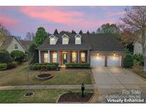 Charming brick home featuring a manicured lawn, dormer windows, and an attached two-car garage at sunset at 331 Miners Cove Way, Fort Mill, SC 29708