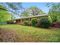 Charming one-story brick home featuring a lush green lawn, mature trees, and colorful shrubs at 422 Sherrill Farm Rd, Lincolnton, NC 28092