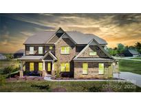 Stunning two-story brick home featuring manicured landscaping and a welcoming covered porch at 8313 Balcony Bridge Rd, Huntersville, NC 28078