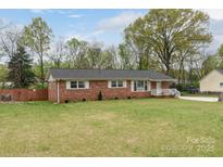Charming brick ranch home with a well-manicured lawn and a cozy, inviting front porch with white railings at 1121 Rembrandt Sw Dr, Concord, NC 28027