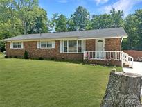 Charming single-story brick home featuring a well-manicured lawn and a cozy, white-railed front porch at 1121 Rembrandt Sw Dr, Concord, NC 28027