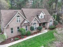 Beautiful brick home featuring a well-maintained yard with mature trees and blooming flowers at 7184 Seagrass Cir, Denver, NC 28037