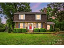 Charming brick home with lush landscaping, red door, and a well-manicured lawn, creating inviting curb appeal at 819 Old Dutch W Rd, Indian Trail, NC 28079