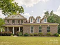 Charming brick home with a landscaped lawn and inviting front porch, featuring dormer windows and a classic design at 2751 Collaroy Rd, Waxhaw, NC 28173