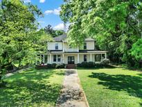 Charming two-story home with inviting front porch and well-manicured lawn, nestled amongst mature trees at 407 Chesterfield Ave, Lancaster, SC 29720