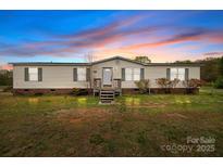 Charming single-story home featuring a well-maintained front yard under a colorful sky at 5110 Old Still Ln, Bessemer City, NC 28016