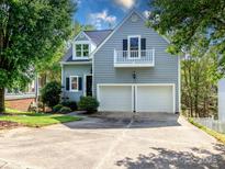 Charming two-story home with light blue siding, a balcony, black shutters, and a two-car garage at 6013 Coaching Inn Ct, Charlotte, NC 28270