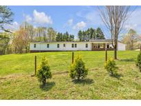 Charming single-story home with a brick accent, surrounded by a lush green lawn and a delicate metal fence at 1975 Old Wilkesboro Rd, Taylorsville, NC 28681
