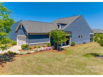 Beautiful blue home featuring a two-car garage, manicured lawn, and stone accents at 4502 Middlebury Ln, Fort Mill, SC 29715