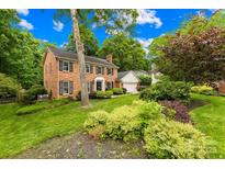 Traditional brick home with black shutters, well-manicured lawn and lush landscaping at 6744 Wheeler Dr, Charlotte, NC 28211
