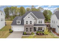 Charming two-story home featuring stone accents, a covered front porch, and a well-manicured lawn, creating curb appeal at 15230 Ravenall Dr, Huntersville, NC 28078