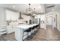 Eat-in kitchen with stainless appliances, white cabinetry, quartz counters, and modern light fixtures at 15230 Ravenall Dr, Huntersville, NC 28078