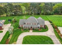 Expansive brick home with manicured lawn and circular driveway on a lush, tree-lined property at 1902 Windmere Dr, Monroe, NC 28110