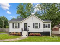 Charming home with a white exterior, black shutters, well manicured lawn and beautifully landscaped flower beds at 2414 Remount Rd, Charlotte, NC 28208