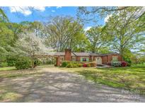 Charming brick home featuring a lush front yard, mature trees, and a convenient carport at 252 Stamey Farm Rd, Statesville, NC 28677