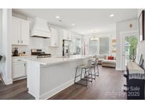 Bright, open kitchen features white cabinets, subway tile backsplash, stainless steel appliances, and a view to the living room at 562 Amalfi Dr, Davidson, NC 28036