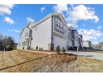 Charming townhome featuring a light gray exterior, a garage, and professional landscaping on a sunny day at 8026 Downy Oak Ln, Charlotte, NC 28269