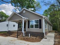 Charming single-story home with neutral siding, black shutters, inviting front porch, and freshly poured concrete at 833 Arlington Ave, Rock Hill, SC 29730