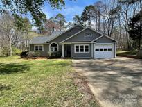 Charming single-story home featuring a gray exterior, attached garage, and well-maintained front yard at 104 Edgewater Nw Dr, Concord, NC 28027