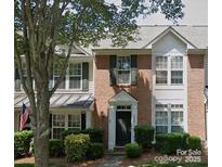 Charming two-story townhouse featuring a brick facade, green shutters, and well-maintained landscaping at 19057 Coachmans Trce, Cornelius, NC 28031
