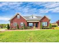Charming, one story red brick home with well-manicured lawn and landscaping at 2103 Parrothead Dr, Monroe, NC 28110