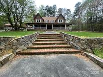 Charming two-story home with brick stairs, a large front porch, and mature trees at 3452 Odell School Rd, Concord, NC 28027