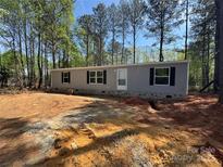 Charming single-story home features a gray exterior, black shutters, and a well-manicured front yard with mature trees at 43290 Isen Rd, New London, NC 28127