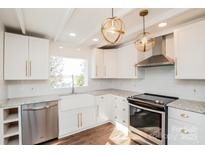 Bright kitchen features white cabinets, stainless steel appliances, granite counters, and stylish light fixtures at 678 Wagner St, Troutman, NC 28166