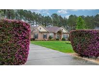 Charming brick home with manicured lawn, blooming bushes, and concrete driveway at 7268 Kiskadee Dr, Denver, NC 28037