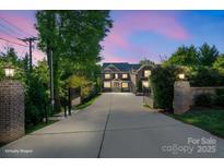 A stately two-story home features a long driveway and picturesque landscaping, creating a welcoming and luxurious curb appeal at 7944 Park Rd, Charlotte, NC 28210