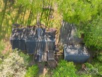 Overhead view of a home with a detached garage, mature trees, and a gravel driveway at 118 Taylor Ct, Mooresville, NC 28117