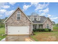 Charming home featuring a stone and vinyl exterior, attached two-car garage, and well-maintained landscaping at 2408 Joes Lake Rd, Shelby, NC 28152