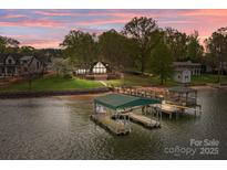 Stunning waterfront home featuring a private boat dock and lush landscaping at sunset at 477 Big Indian Loop, Mooresville, NC 28117