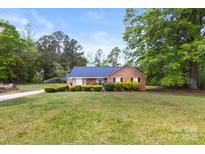 Charming brick home with a blue metal roof, lush green lawn, and manicured landscaping at 5762 Hightower Rd, Fort Lawn, SC 29714