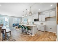 Modern kitchen features white cabinets, stainless appliances, an island with seating, and an open floor plan at 6427 Mallow Crossing Ln, Charlotte, NC 28213