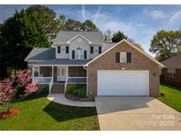 Charming two-story home with a brick facade, covered porch, manicured lawn, and attached two-car garage at 121 Shagbark Ln, Mooresville, NC 28115