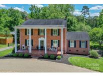 Classic brick home with a charming front porch, rocking chairs, and manicured landscaping at 203 Mt Holly Huntersville Rd, Huntersville, NC 28078
