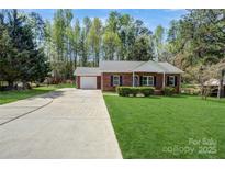 Charming brick ranch home with a well-manicured front lawn, a single-car garage, and a long driveway at 6549 Wesbrook Dr, Charlotte, NC 28214