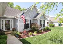 Charming single-story home with manicured lawn, flower beds, and an American flag at 7515 Shadowstone Dr, Charlotte, NC 28270