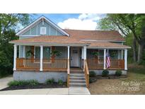 Charming single-story home featuring a cozy front porch with wood railings and stairs at 925 14Th St, Lancaster, SC 29720