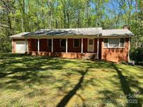 Charming brick ranch with a covered front porch and a well-manicured lawn at 1199 Riding Trail Ln, Concord, NC 28027