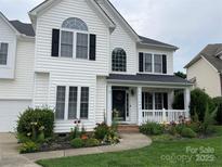 Charming two-story home with white siding, black shutters, covered porch, and inviting front yard flower garden at 17309 Knoxwood Dr, Huntersville, NC 28078
