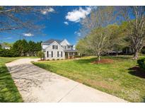 Charming two-story home with stone facade, black shutters, and a well-maintained lawn and long driveway at 2004 Ptarmigan Ct, Waxhaw, NC 28173