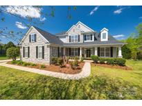 Charming two-story home showcasing a stone facade, manicured landscaping, and inviting front porch with dark shutters at 2004 Ptarmigan Ct, Waxhaw, NC 28173
