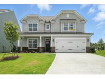 Charming two-story home featuring a gray exterior, manicured lawn, and a two-car garage at 2017 Embassy Ct # 51, Charlotte, NC 28213